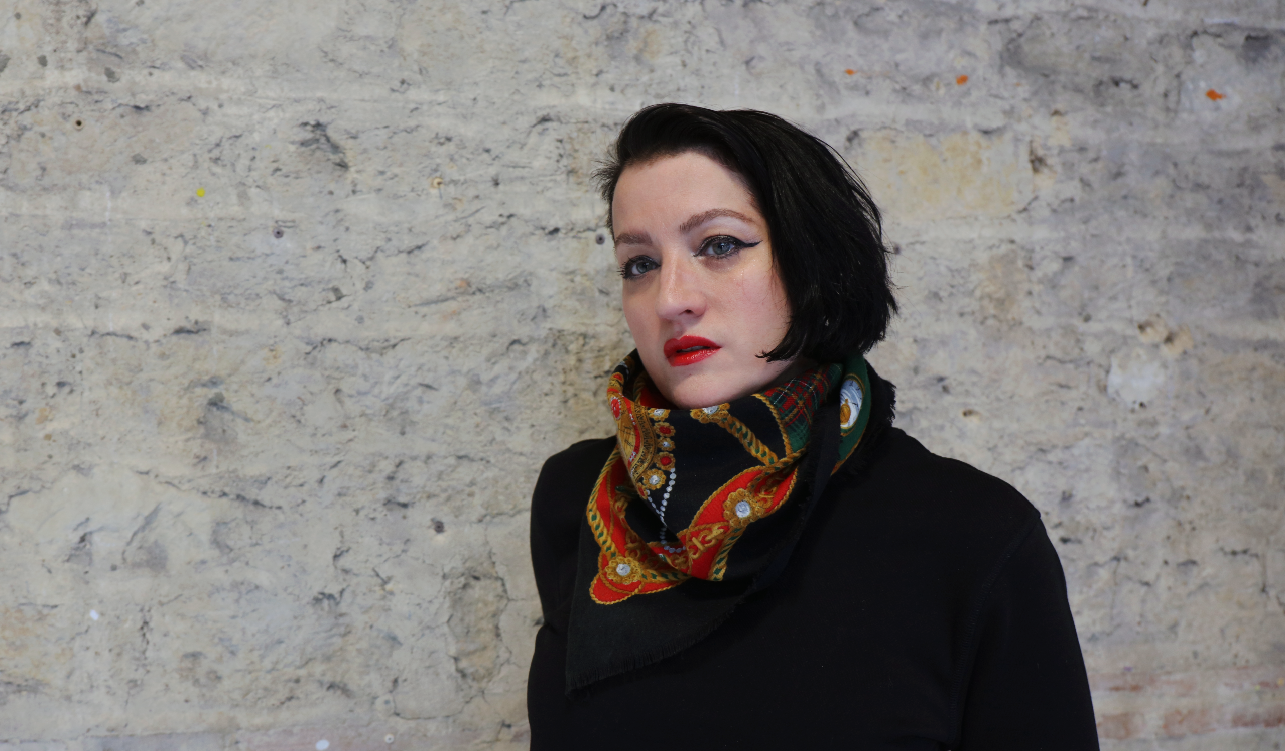 Woman looking at camera in front of a light brick wall