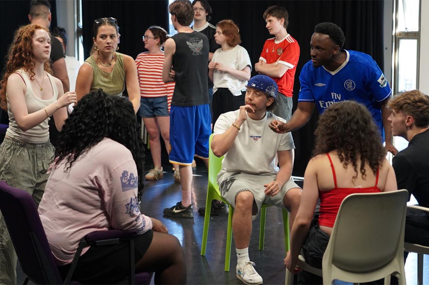 A group of young people sat and stood in a group talking.