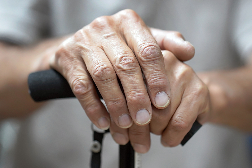 Frailty image showing an older person's hands holding a walking stick